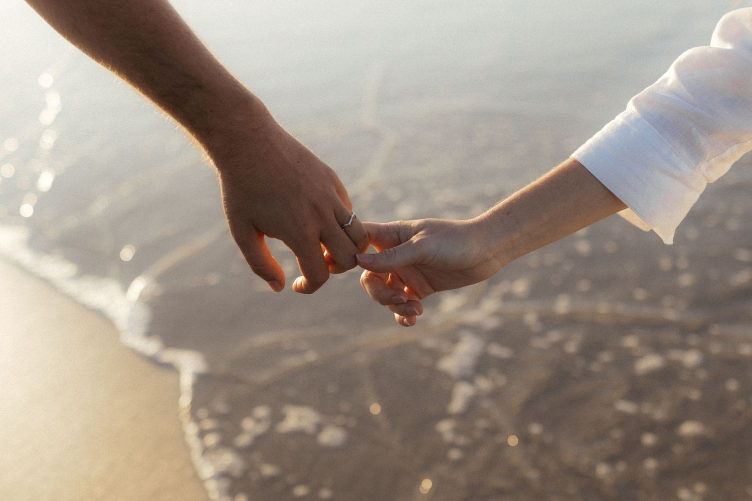 A couple holds hands during a sunset engagement photo session on a scenic mountain overlook.