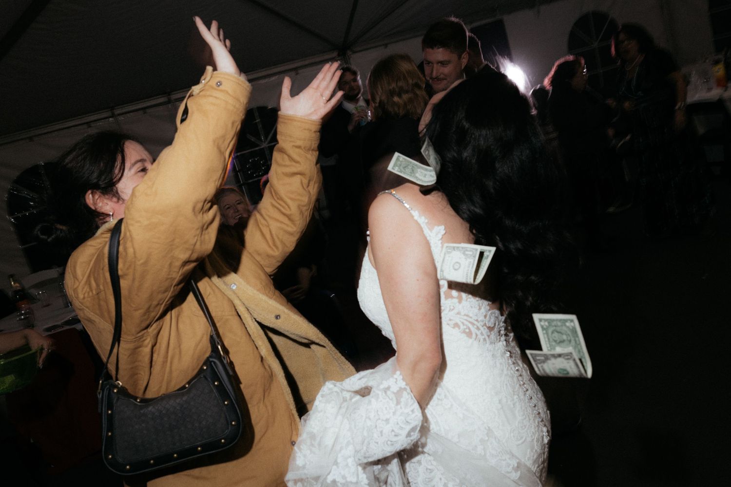Wedding celebration with guests dancing and celebrating in a dimly lit venue.