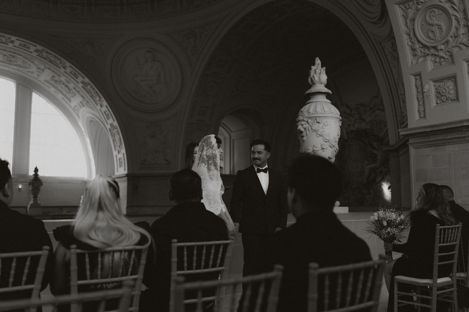 Wedding ceremony setup in a grand hallway with classical architecture and chiavari chairs.