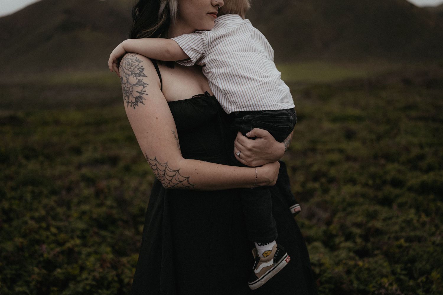 An intimate family embrace photographed in moody lighting with mountains in the background.