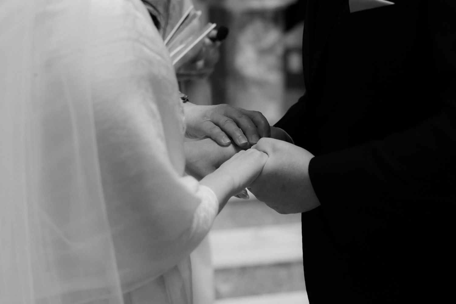 A couple in wedding attire exchanges rings during an intimate ceremony at the altar.