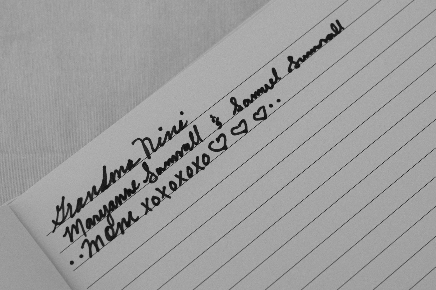 Black and white handwritten signatures on paper show multiple overlapping cursive writing samples.