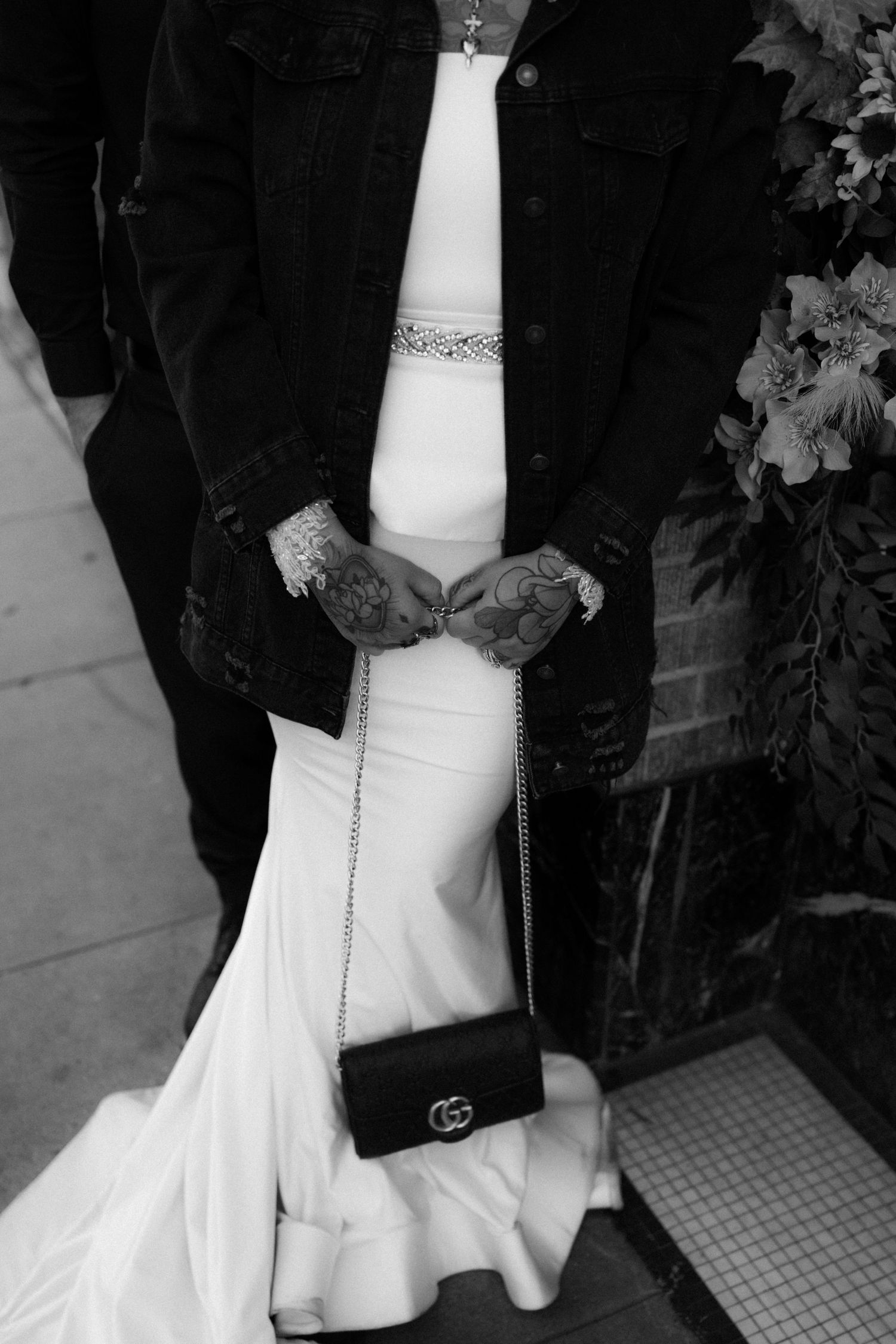 Close-up details of white wedding dress train against brick and tile floor.
