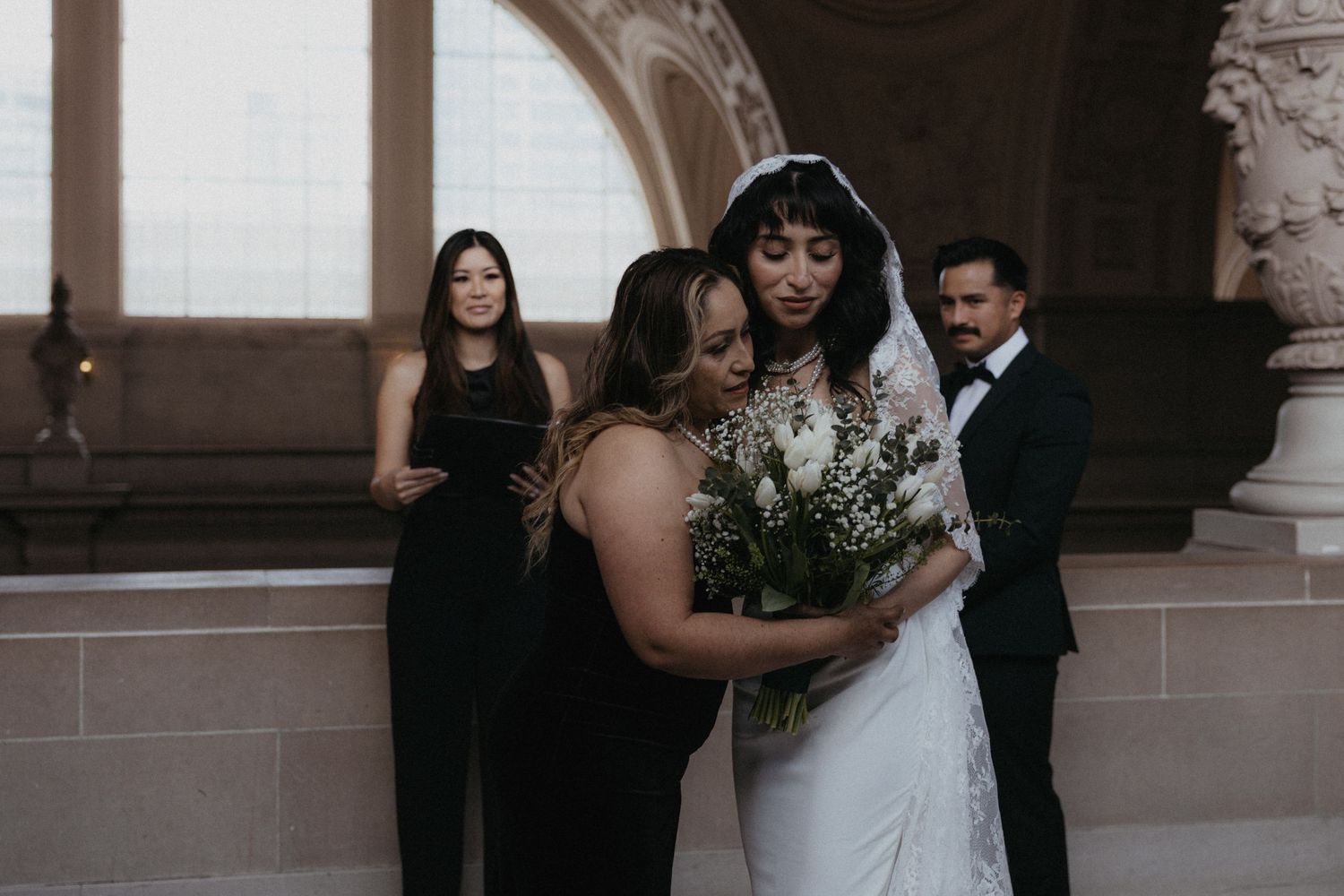 Wedding party members gathering in an elegant hallway with architectural details.