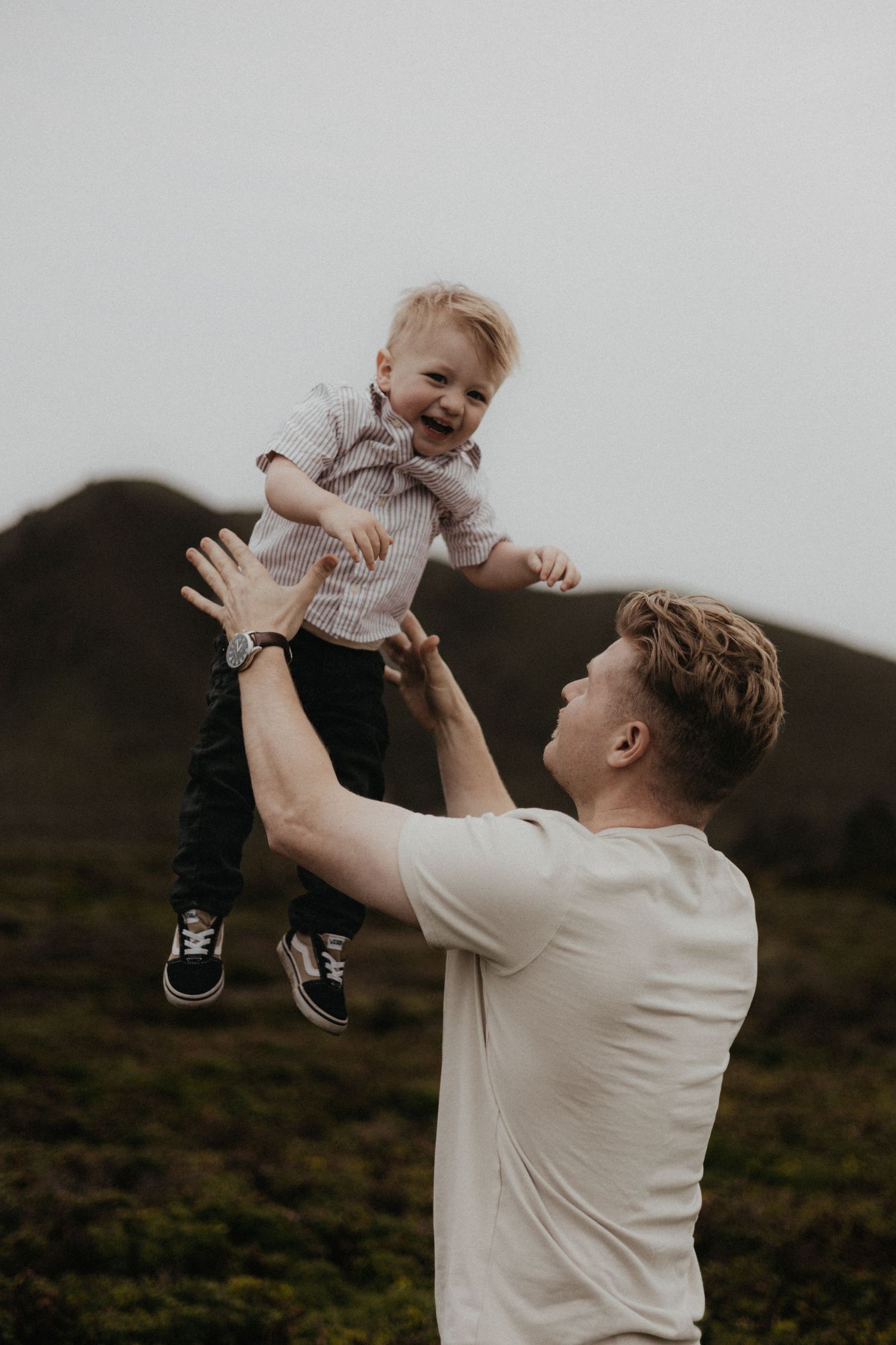 A series of four connected photos showing a person in a white shirt lifting and playing with a baby outdoors.
