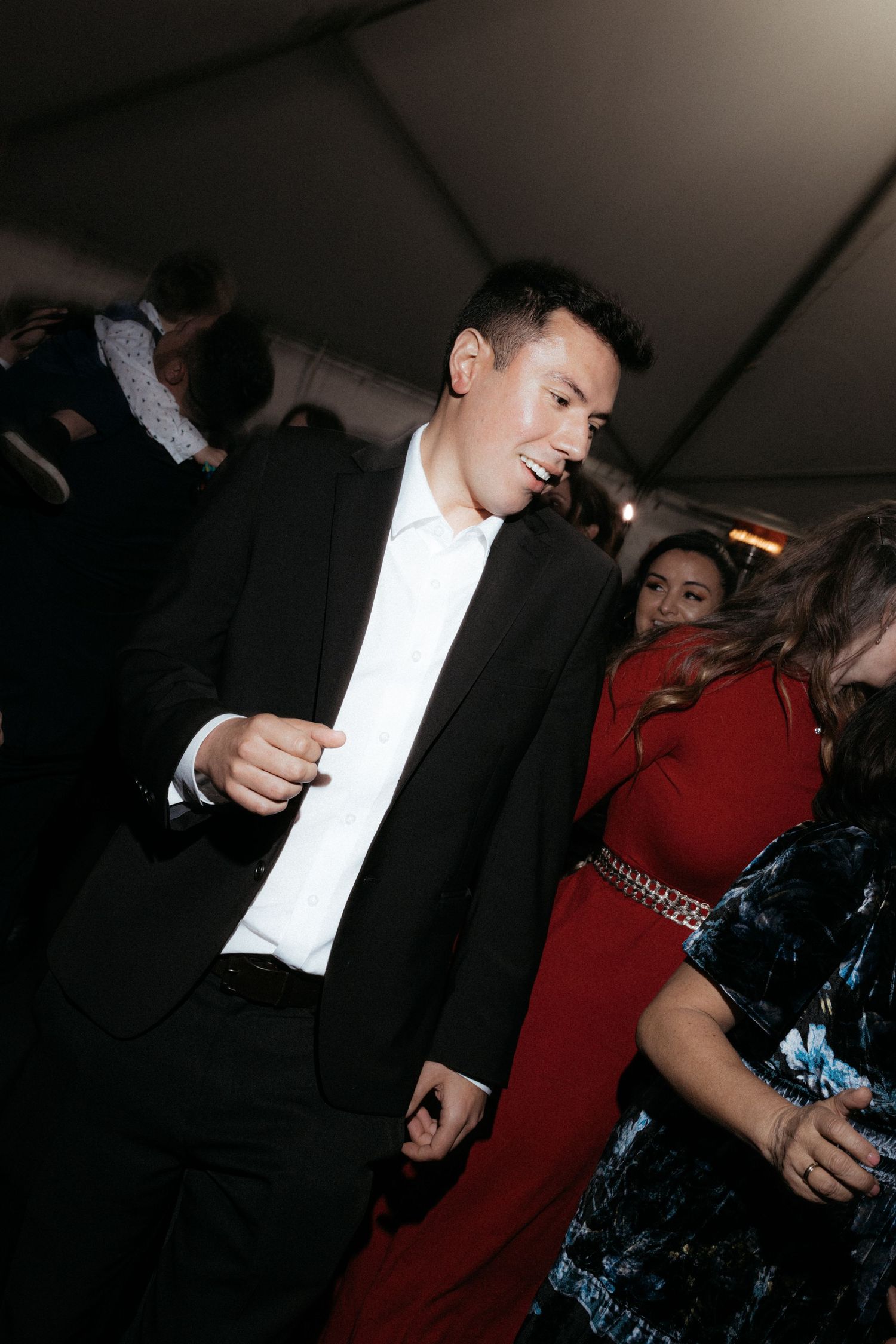 People enjoying themselves while dancing at an indoor evening celebration event.