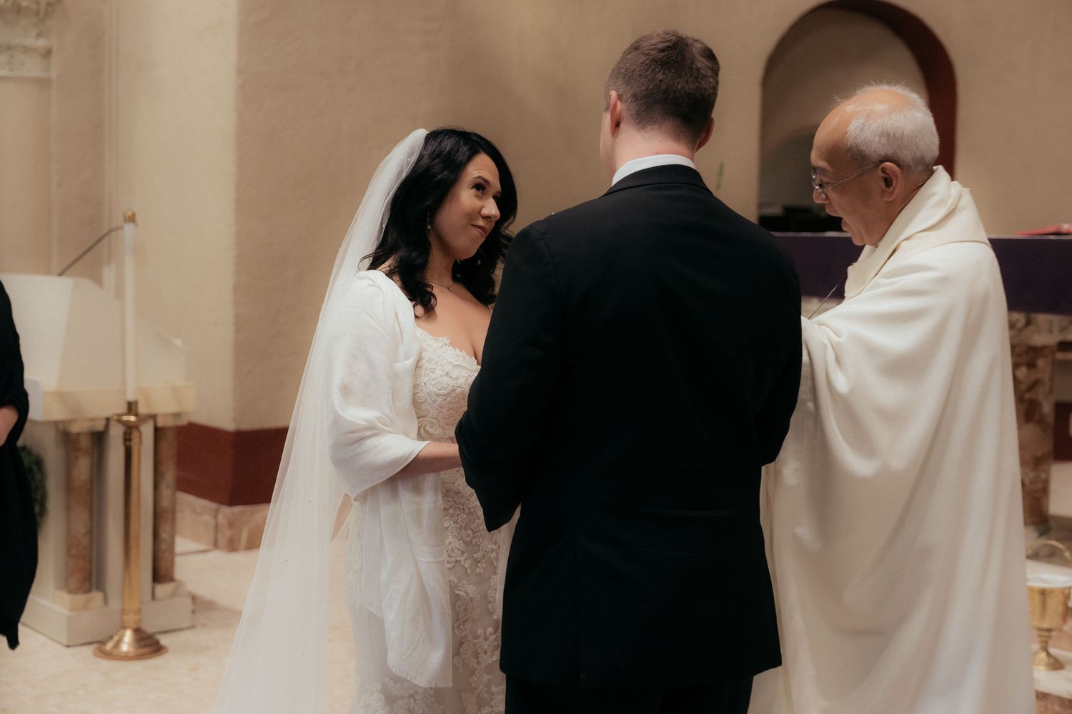 A couple stands at the altar during their wedding ceremony as the priest performs the marriage ritual.