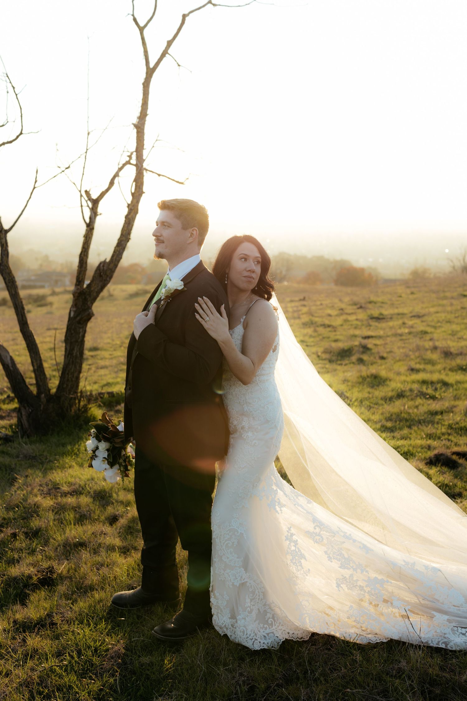Romantic sunset wedding photos in a field with flowing white dress and veil.