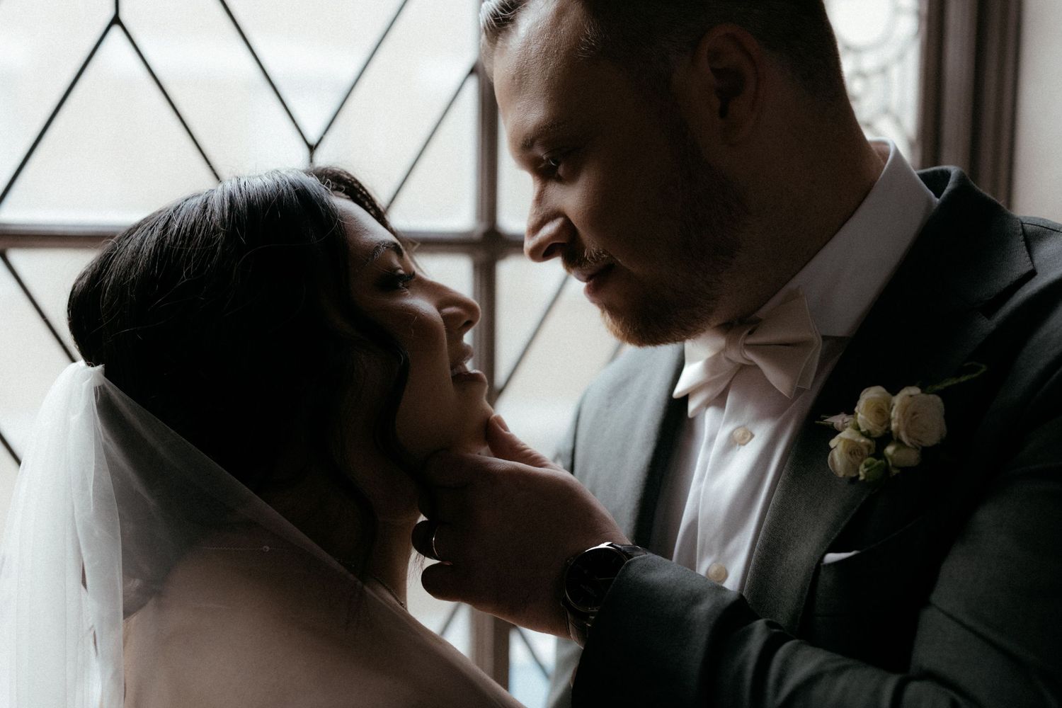 A couple shares an intimate moment during their wedding ceremony, leaning in close together in black and white.