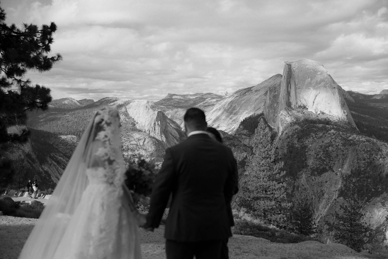 Bride and groom hold hands overlooking Half Dome at Yosemite National Park.