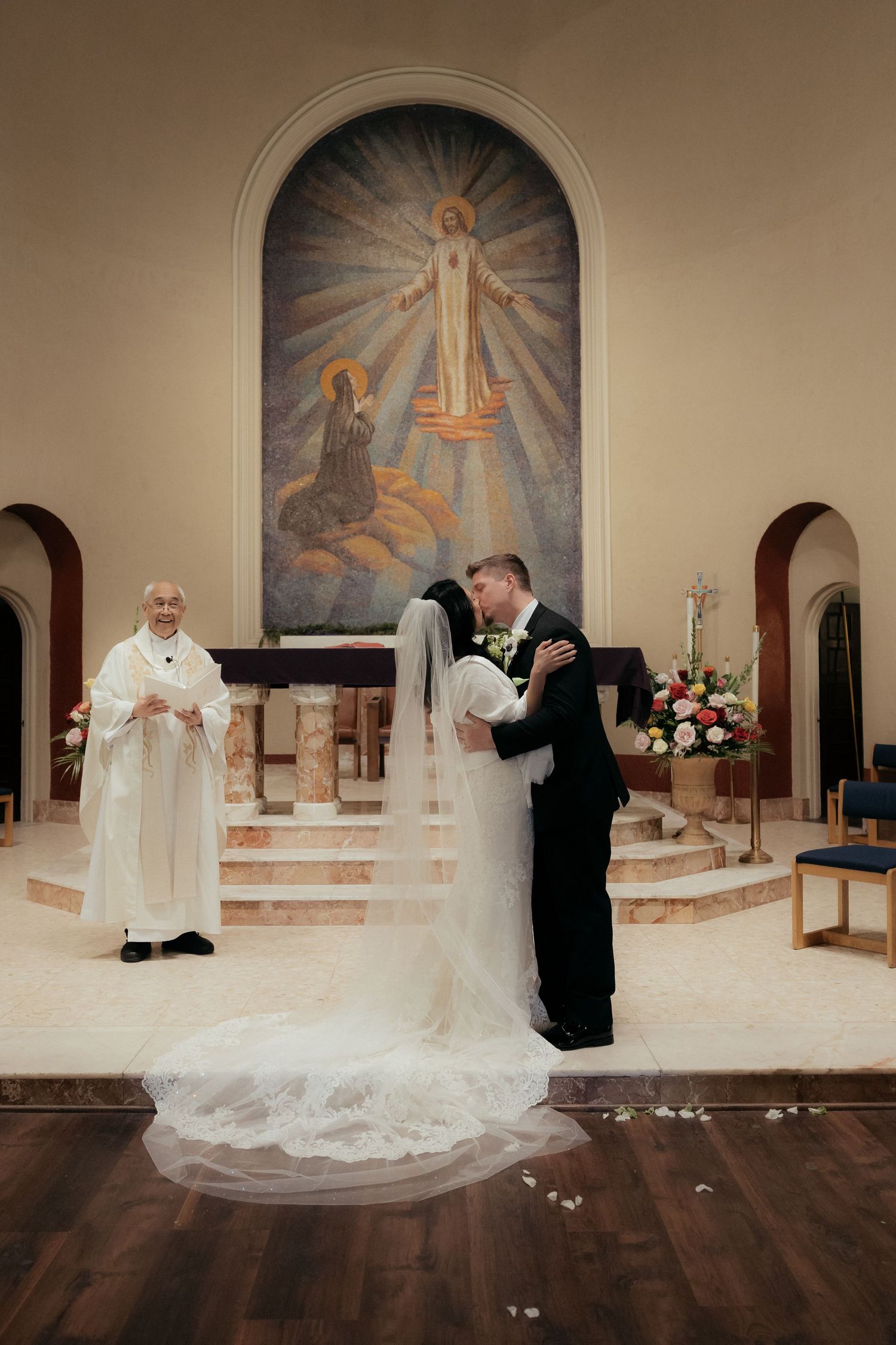 A wedding ceremony takes place before religious murals in a church sanctuary.