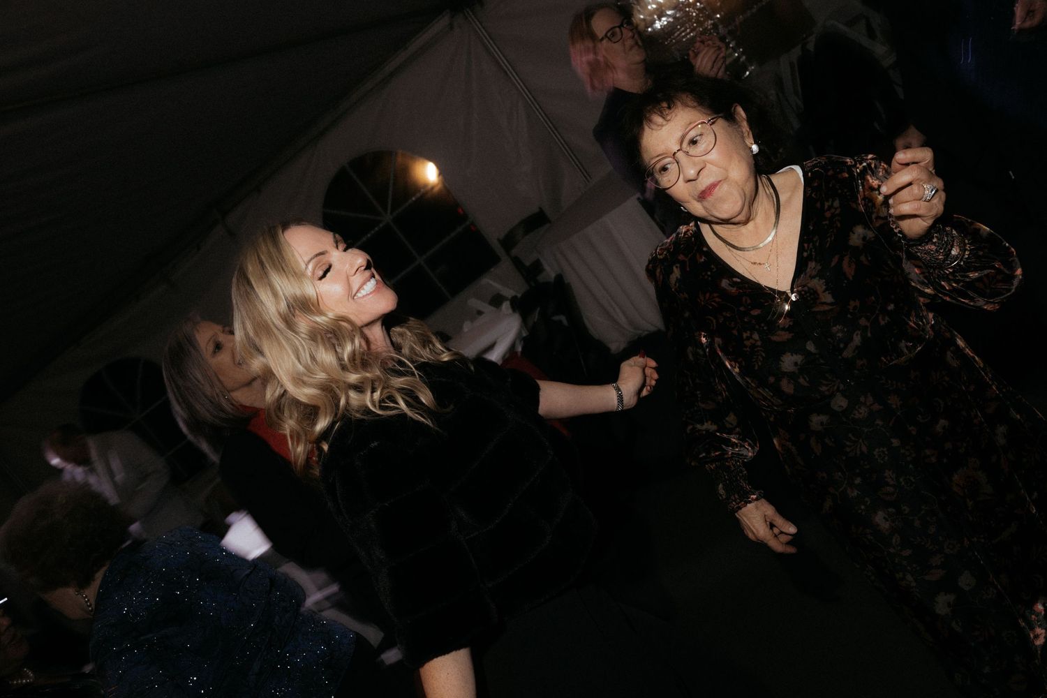 Partygoers socializing in a dark reception venue with festive lighting.