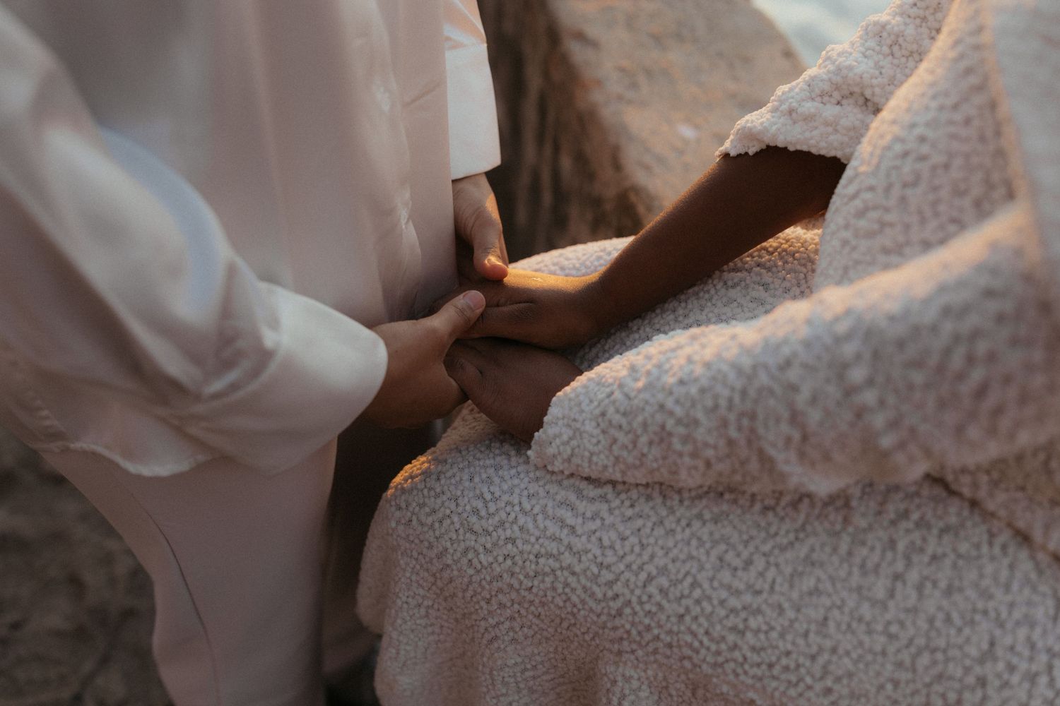 Close-up of hands holding onto delicate white lace fabric in soft natural lighting.