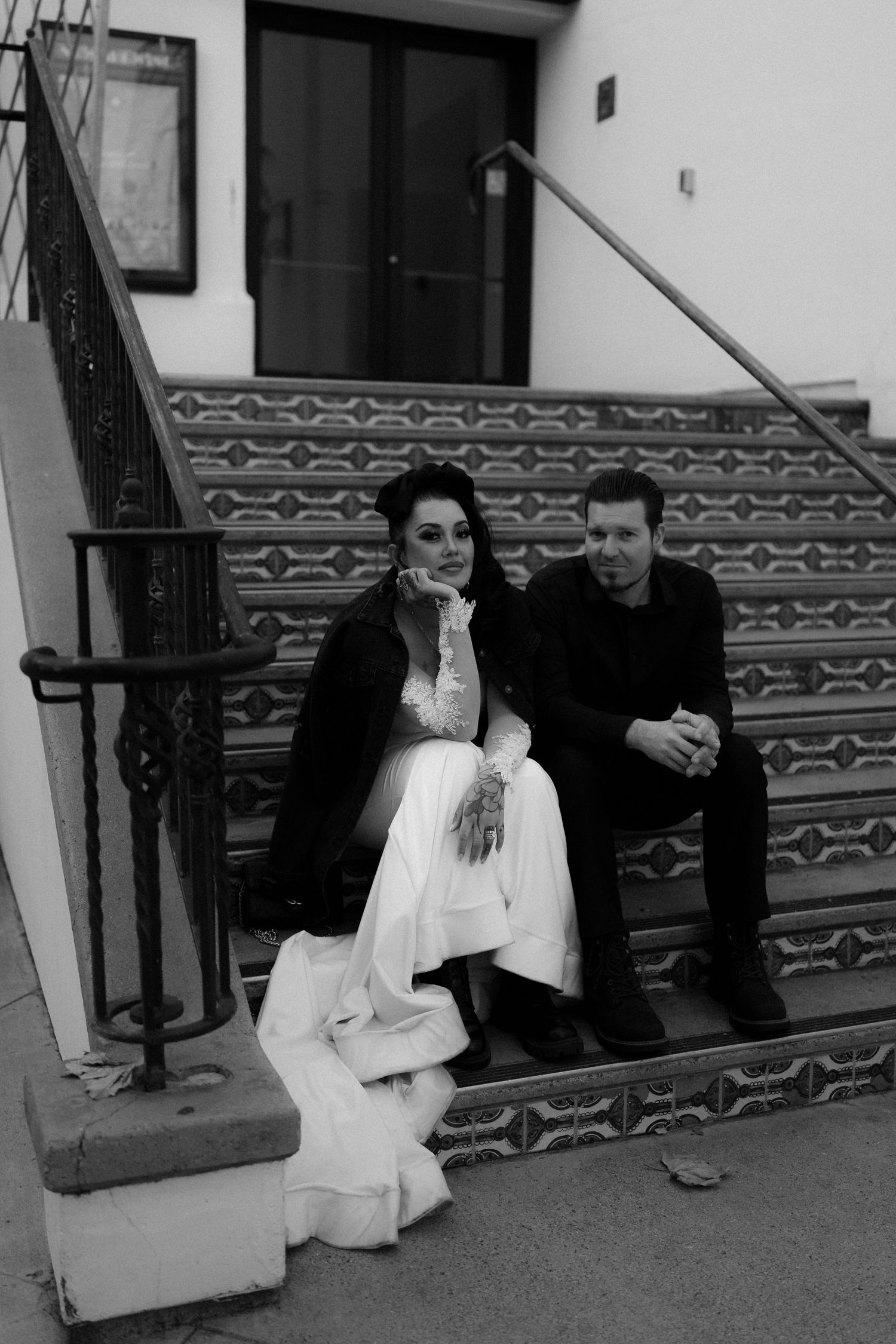 Black and white photo of a couple relaxing on theater steps with geometric patterns.