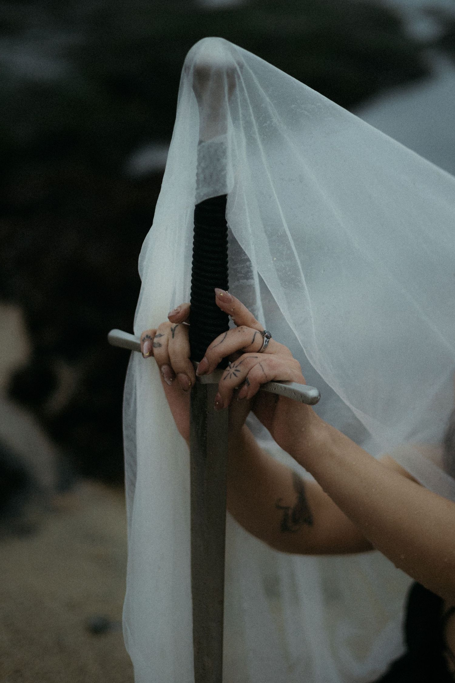 Close-up shot of hands adjusting delicate white wedding veil fabric against dark background.