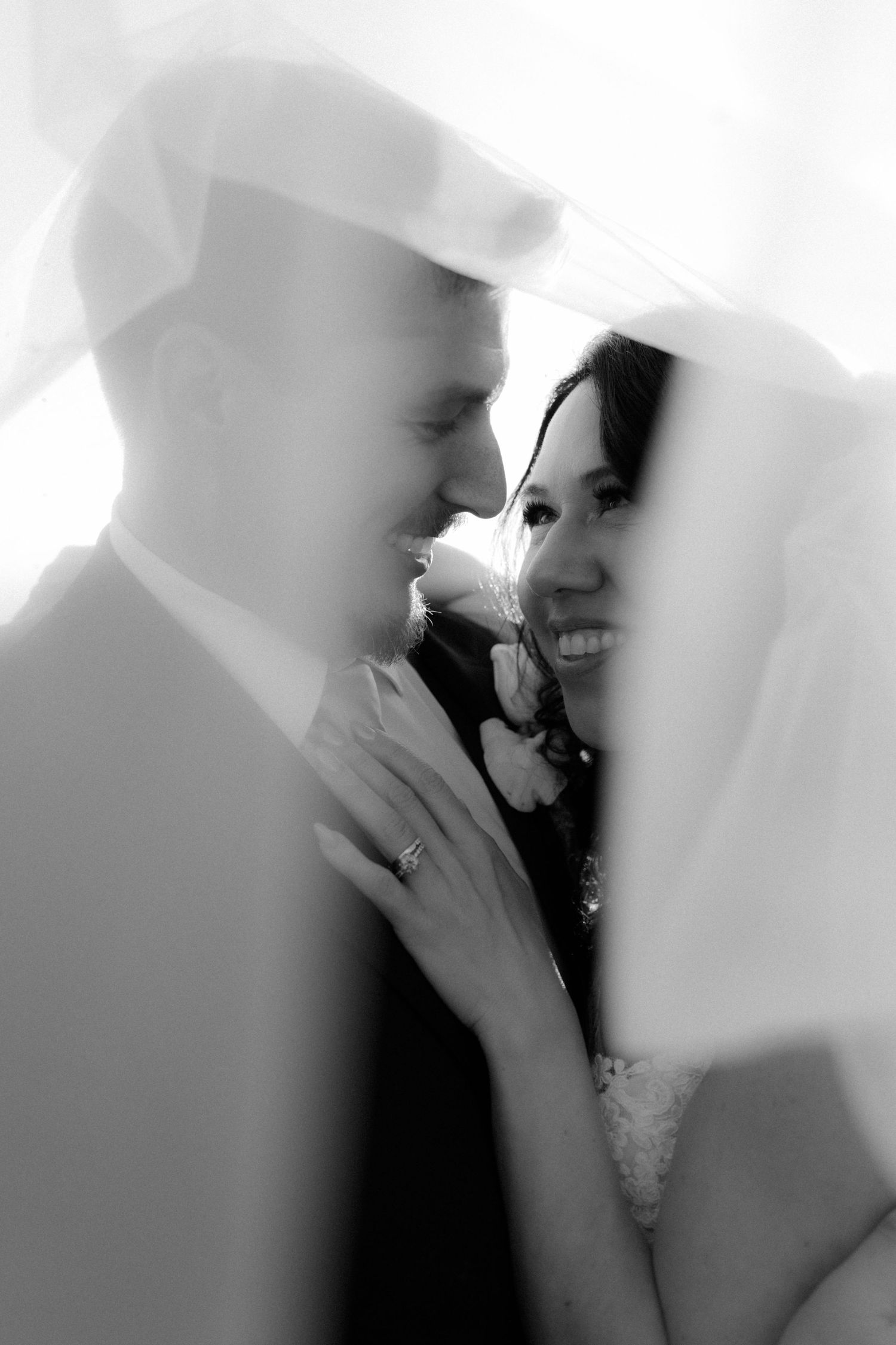 Romantic black and white wedding photo series showing tender moments between newlyweds under a veil.