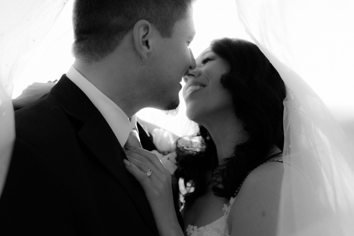 Silhouetted couple shares romantic kiss during their wedding ceremony with dramatic backlighting.
