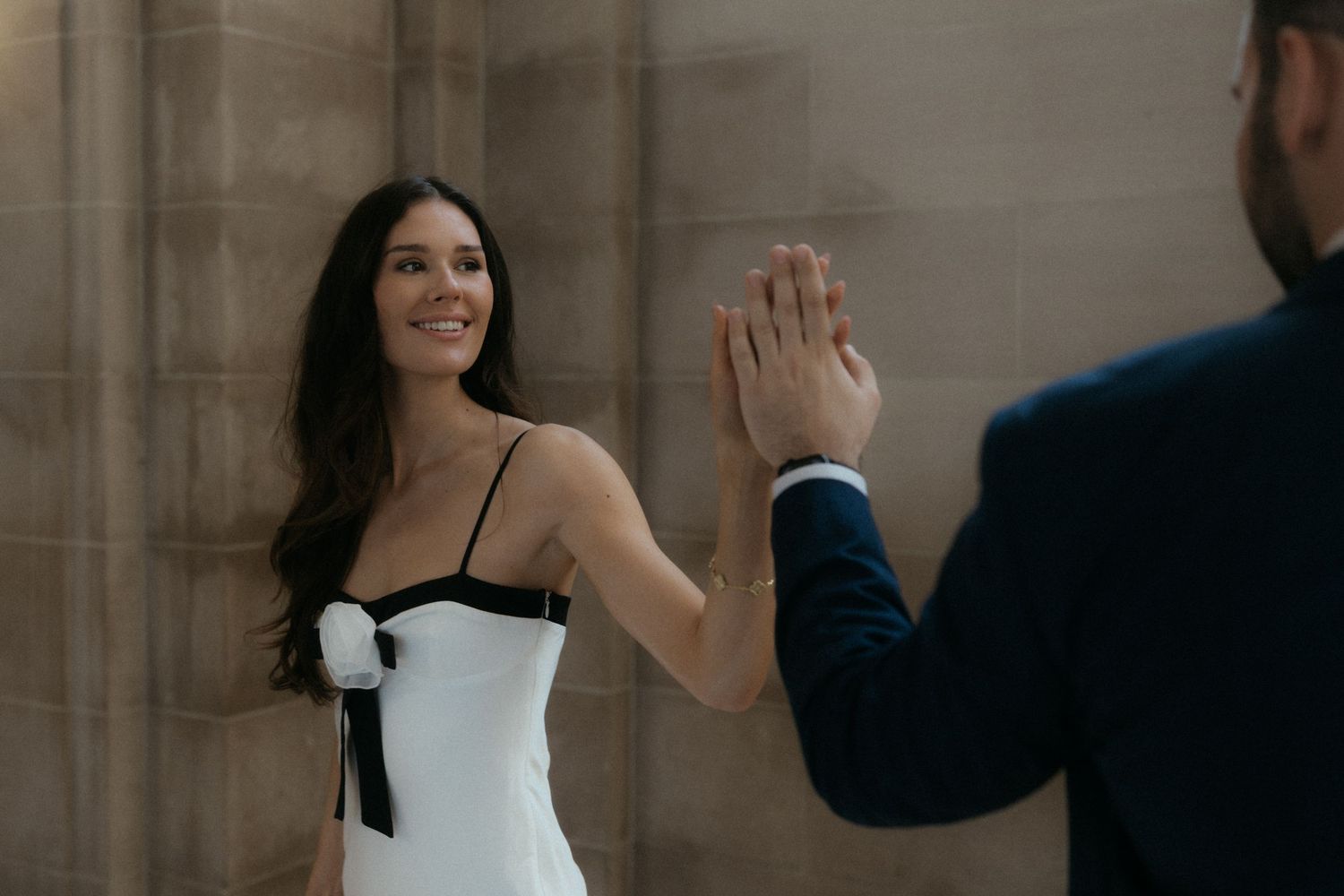 A couple in formal wedding attire shares a tender moment in a stone-walled venue.