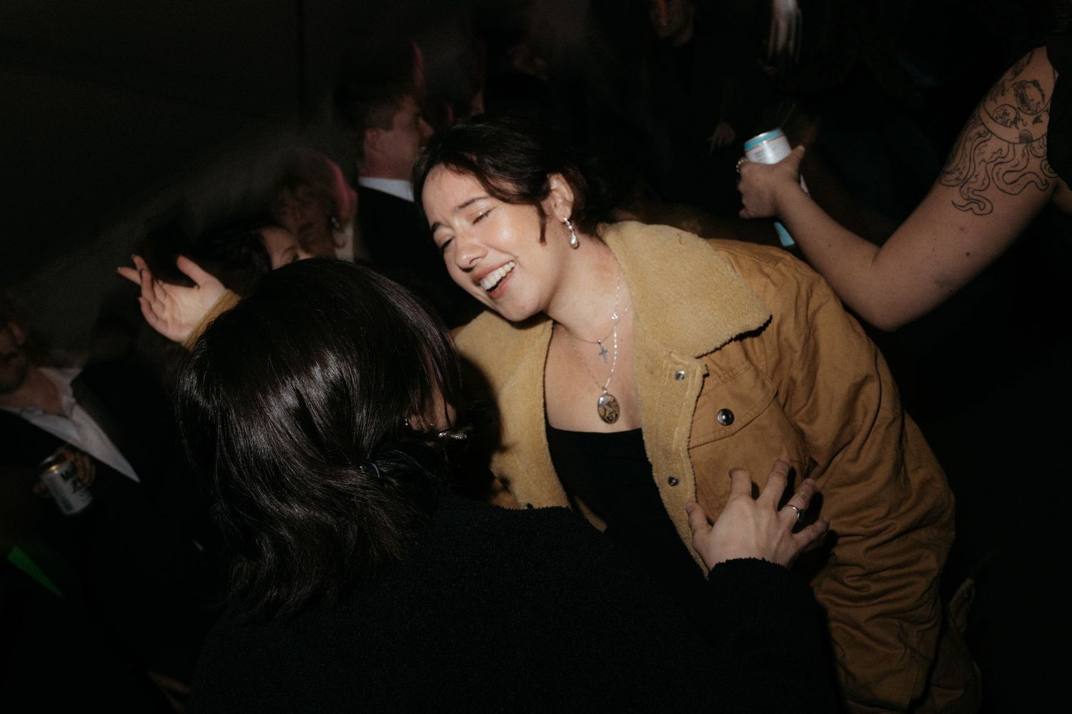 People dancing and socializing at a dimly lit party or nightclub event.