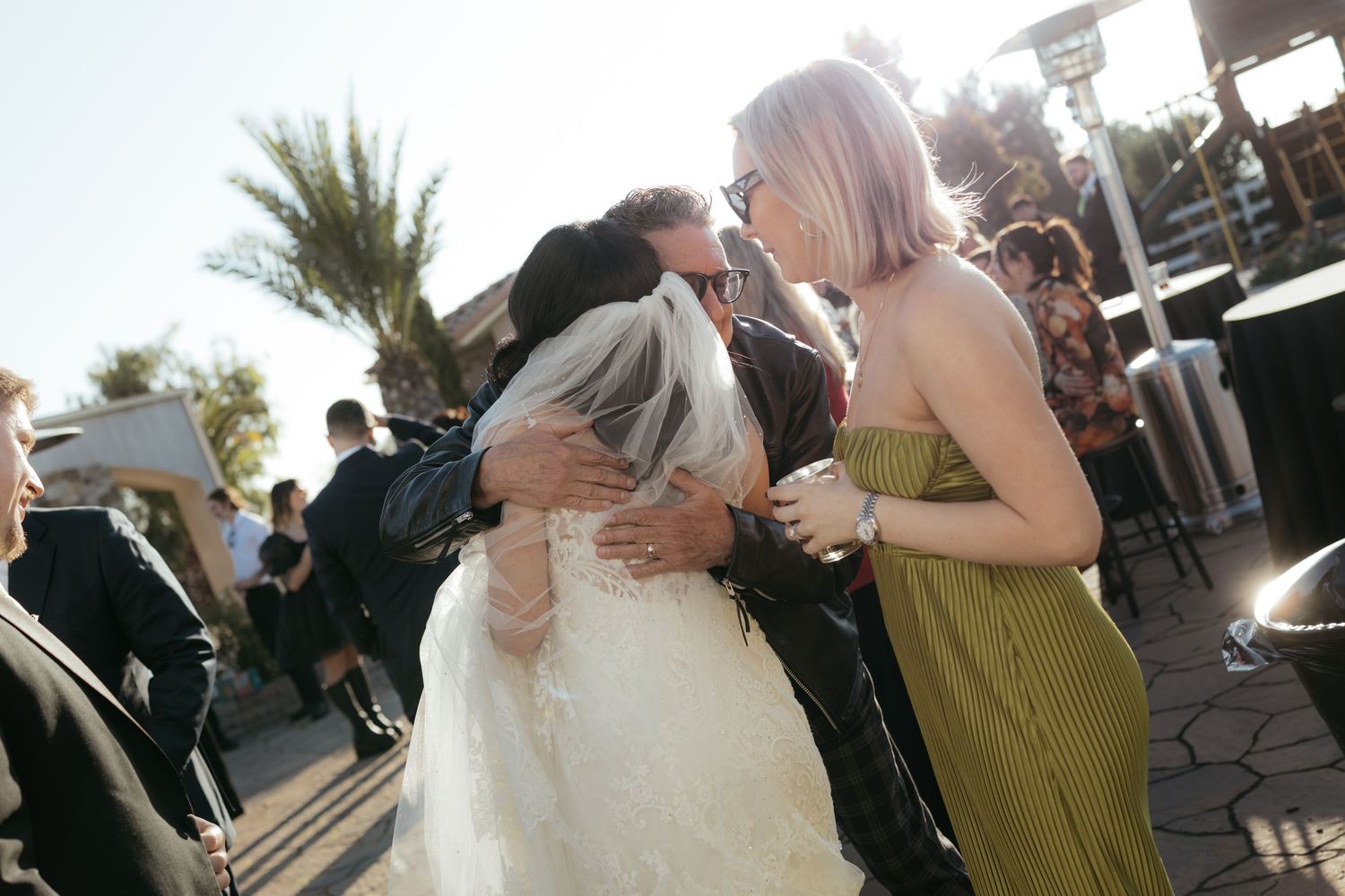 Wedding guests celebrating outdoors during golden hour with palm trees in the background.