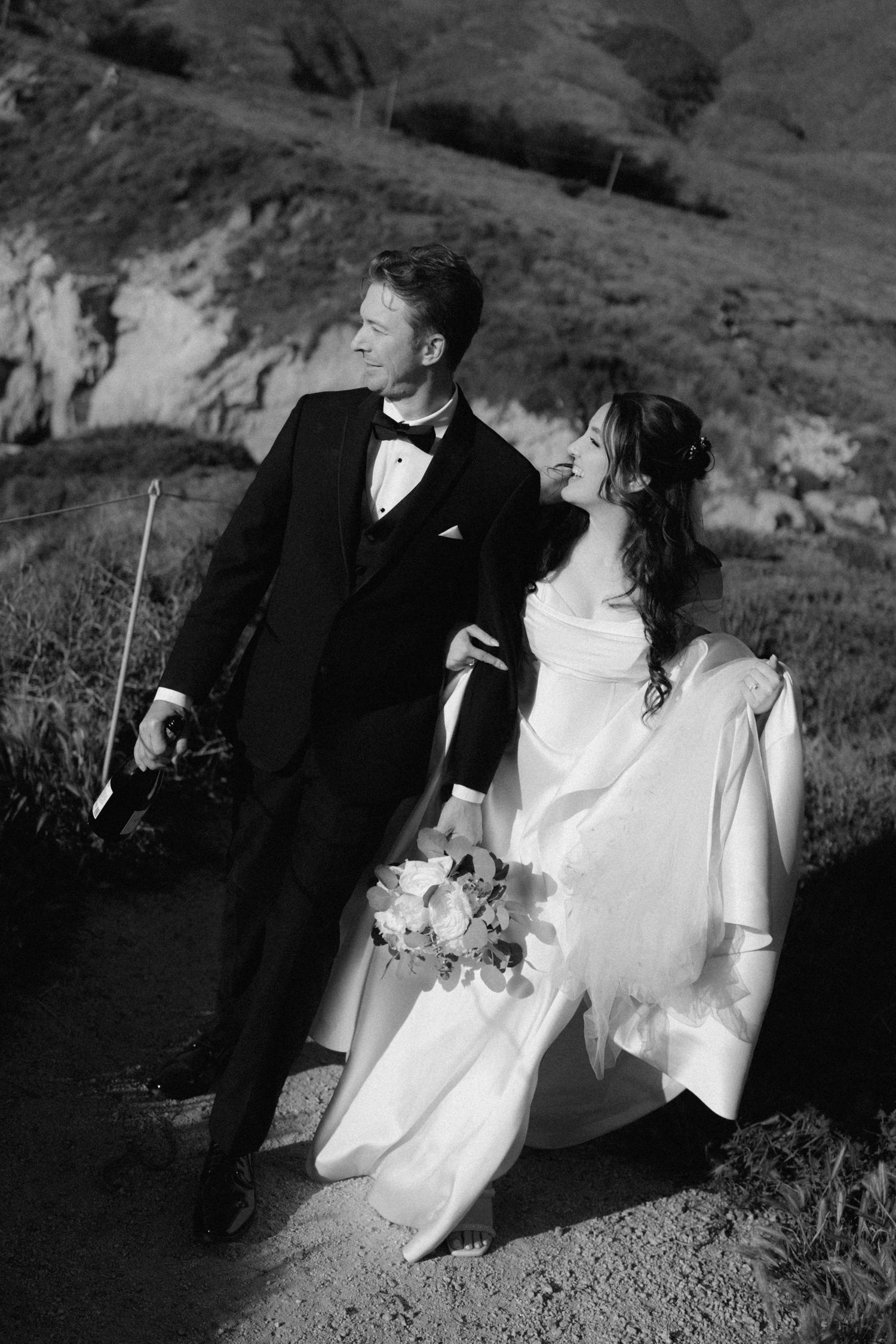 Black and white photo of bride and groom posing on a scenic coastal path in Carmel-by-the-Sea, California.