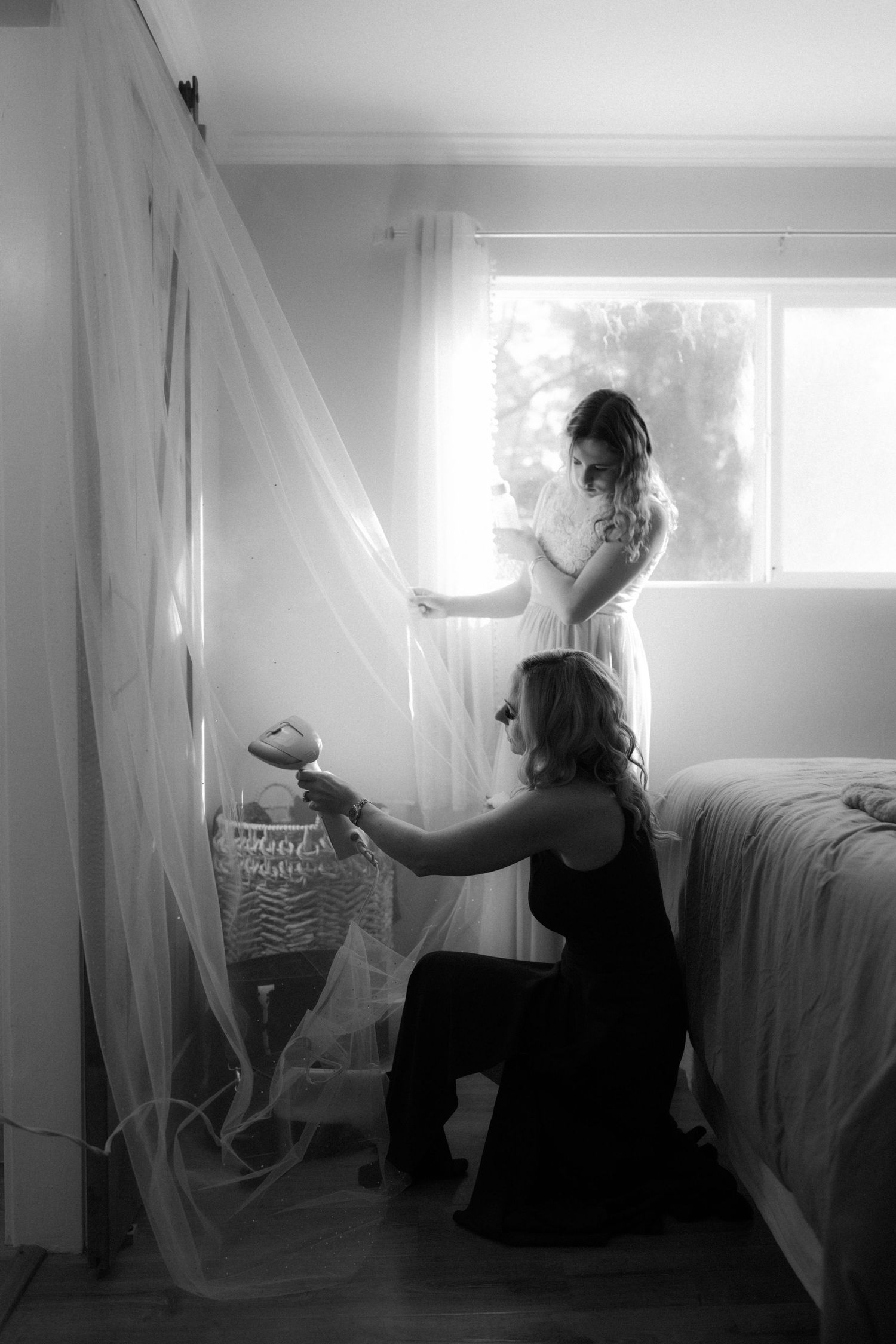 Artistic black and white photos show a person working with sheer fabric in a bright interior space.