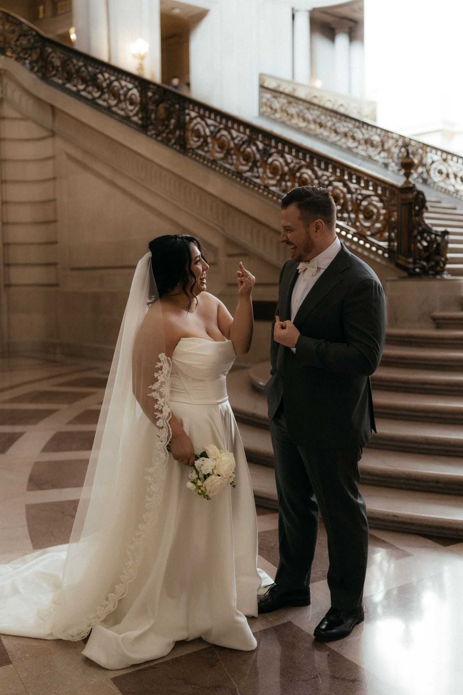 Sepia toned wedding photos showing a couple in formal attire posing on grand staircase in historic building.
