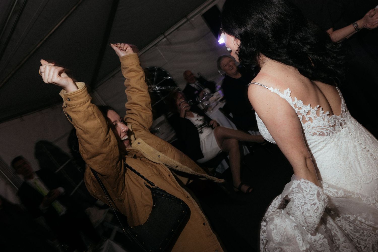 Couples dancing together at a dimly lit wedding reception with dramatic lighting and shadows.