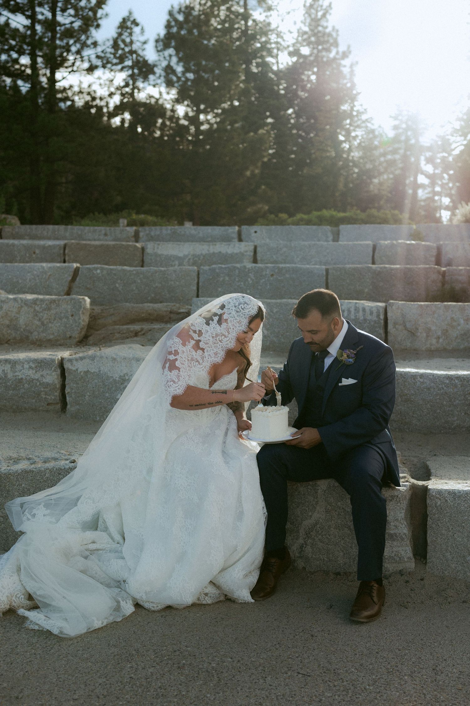 Bride and groom cut heart-shaped wedding cake on stone steps in Yosemite forest.