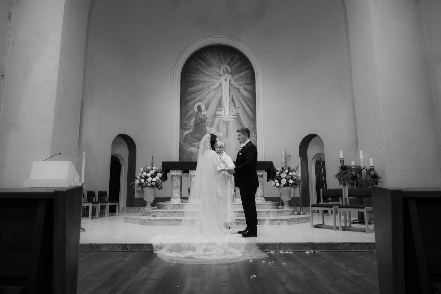 Black and white photo of a wedding ceremony in a church sanctuary.