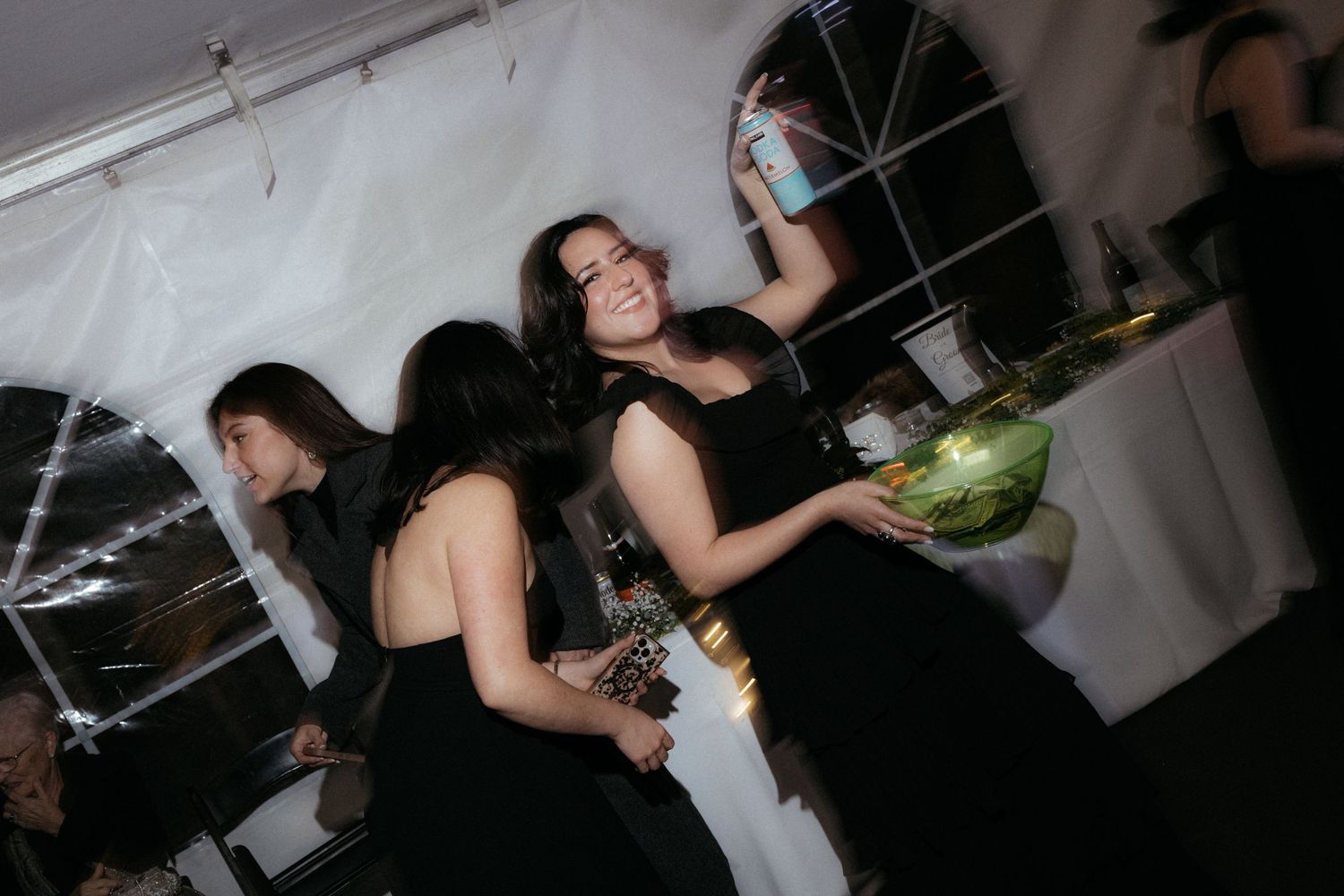 Party guests in dark attire enjoying refreshments at an evening celebration.