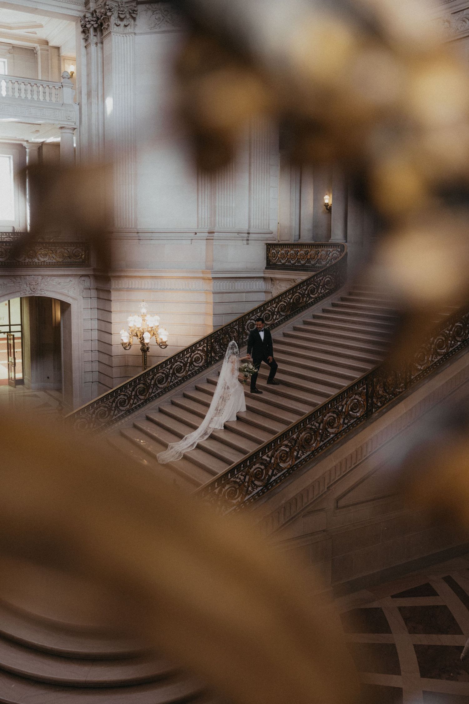 Bride and groom descend grand staircase at San Francisco City Hall wedding.
