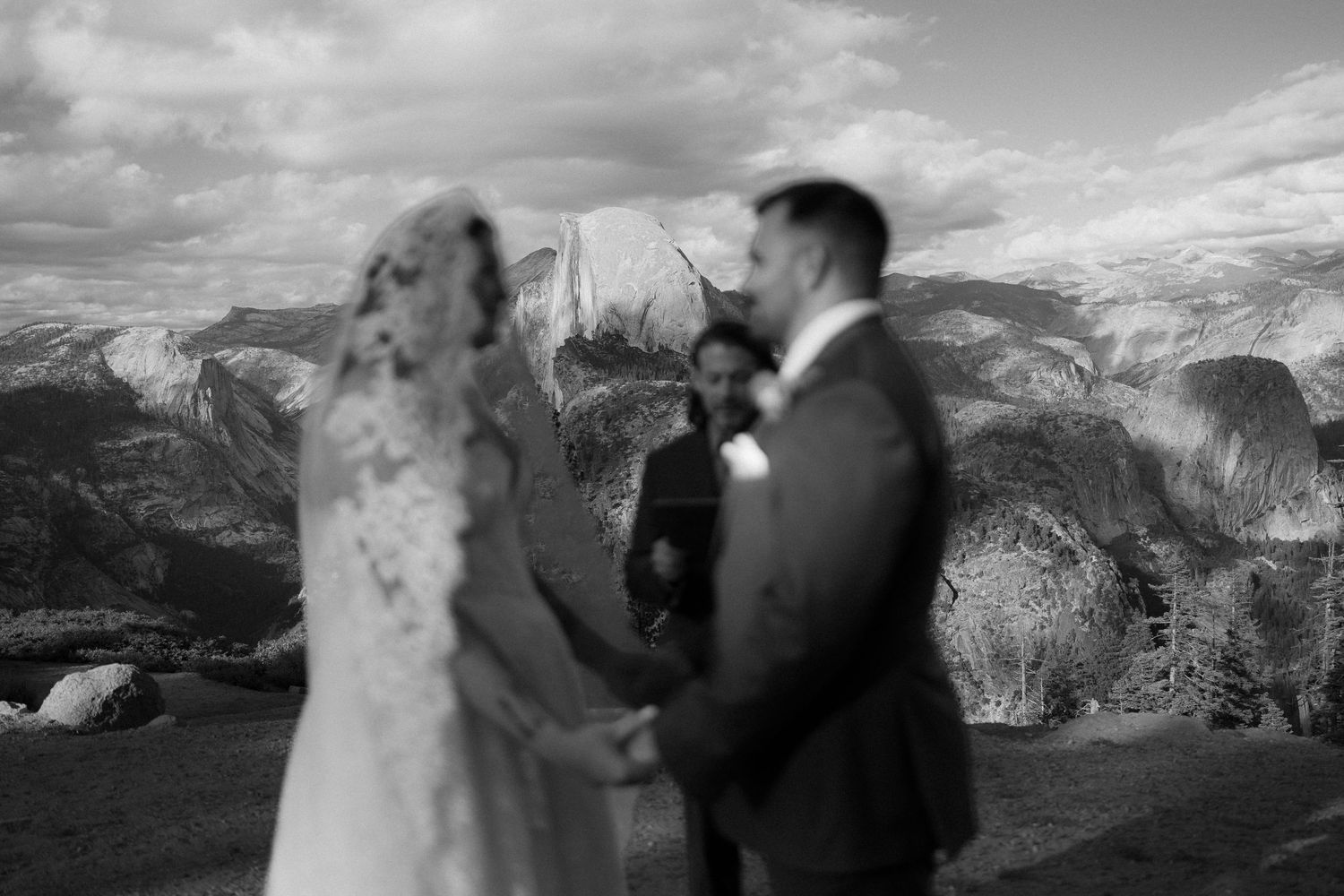 Black and white photo of couple exchanging vows with Half Dome Yosemite backdrop.