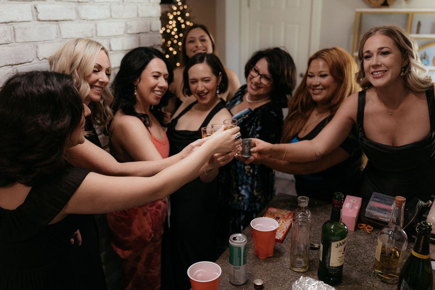 A group of friends laugh and embrace while enjoying drinks at a social gathering.