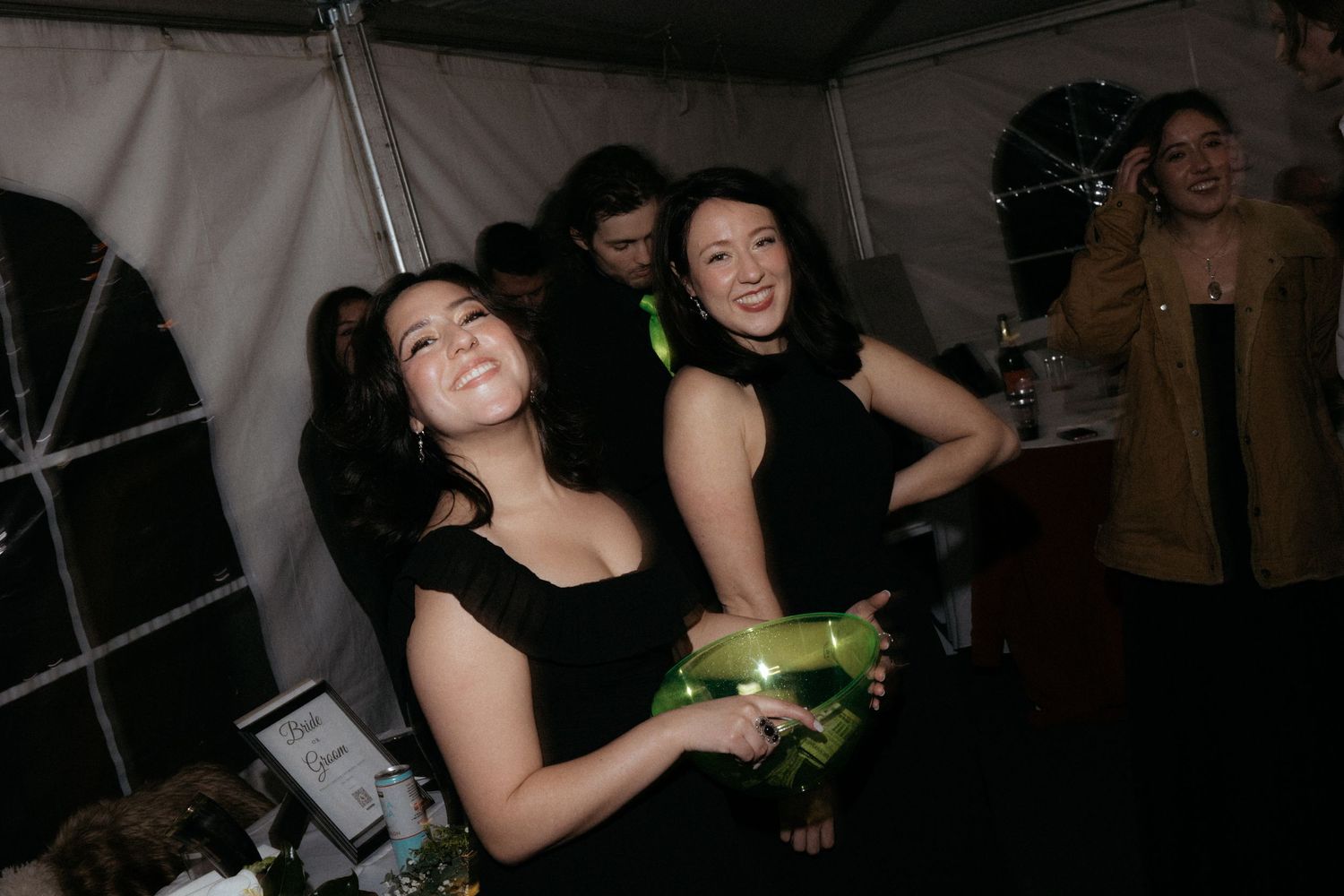 Wedding guests dance and celebrate at a dimly lit reception party.