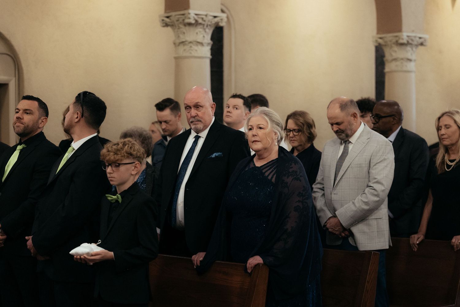 A row of people standing in church pews during a religious service.