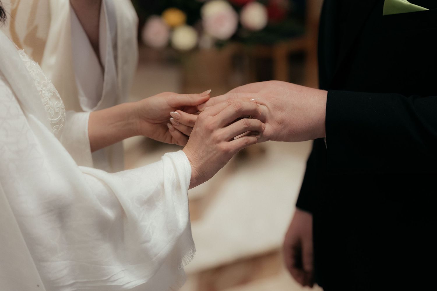 Close-up shot of hands exchanging rings during a wedding ceremony.