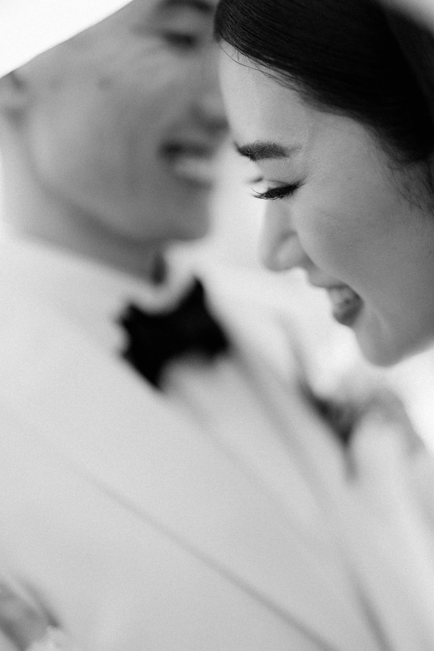 Black and white wedding photo of a smiling couple in close embrace, groom in bow tie, bride with elegant makeup.