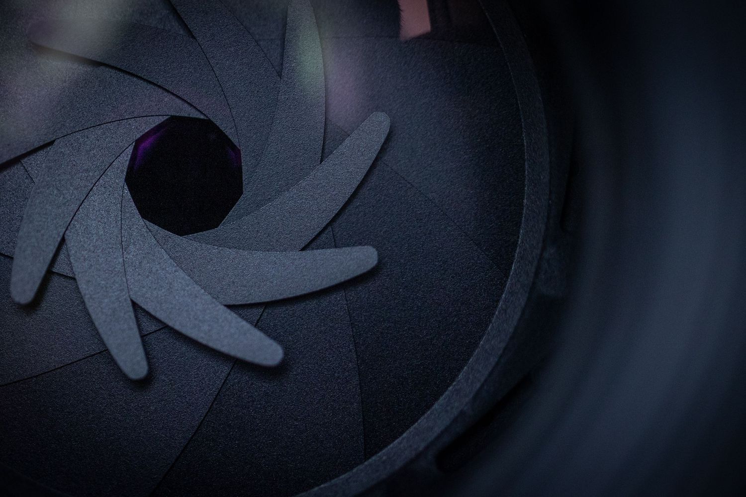 Close-up view of a camera lens aperture blades in a dark moody setting.