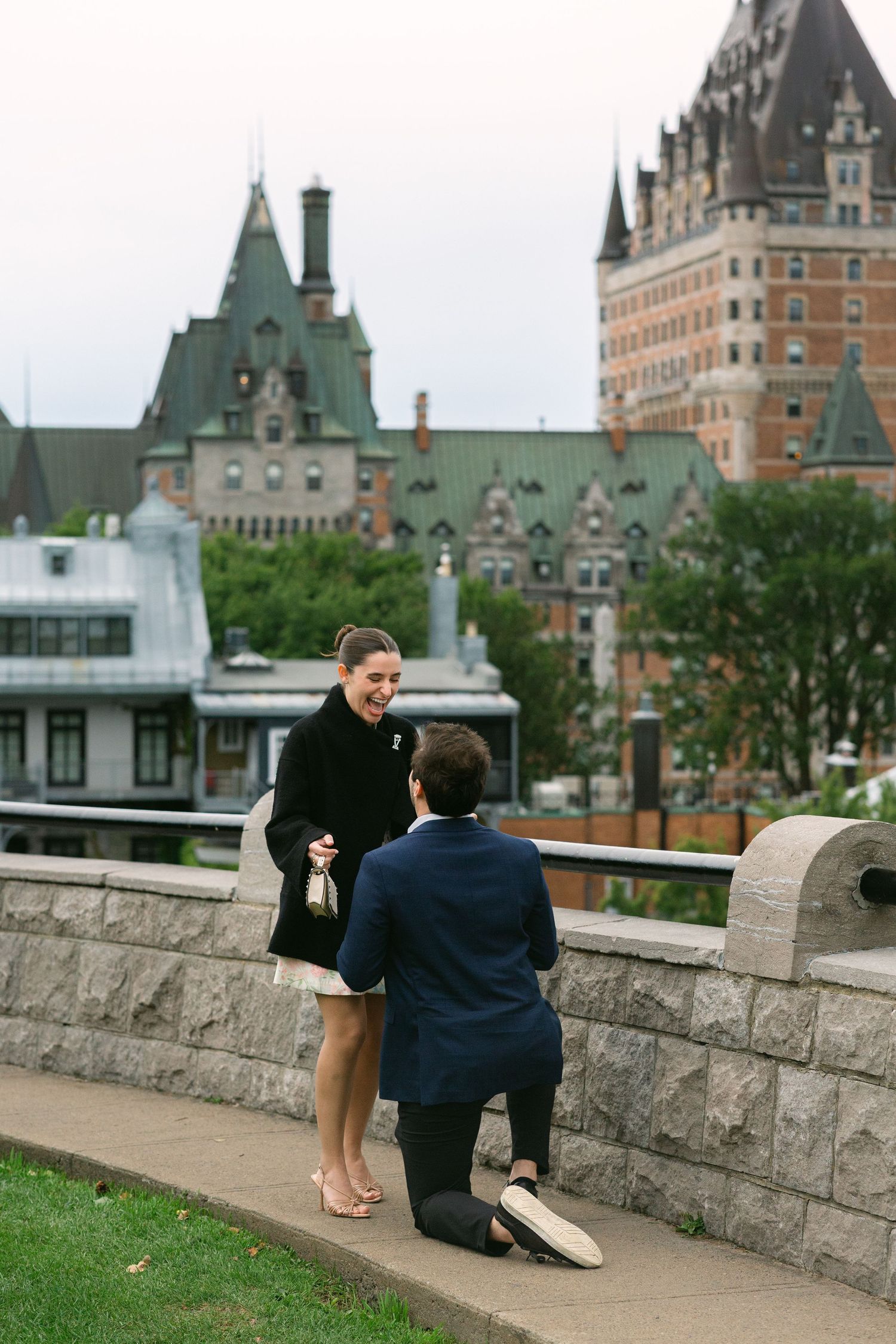 Man proposing on one knee to a woman in front of Château Frontenac in Quebec City, Canada.