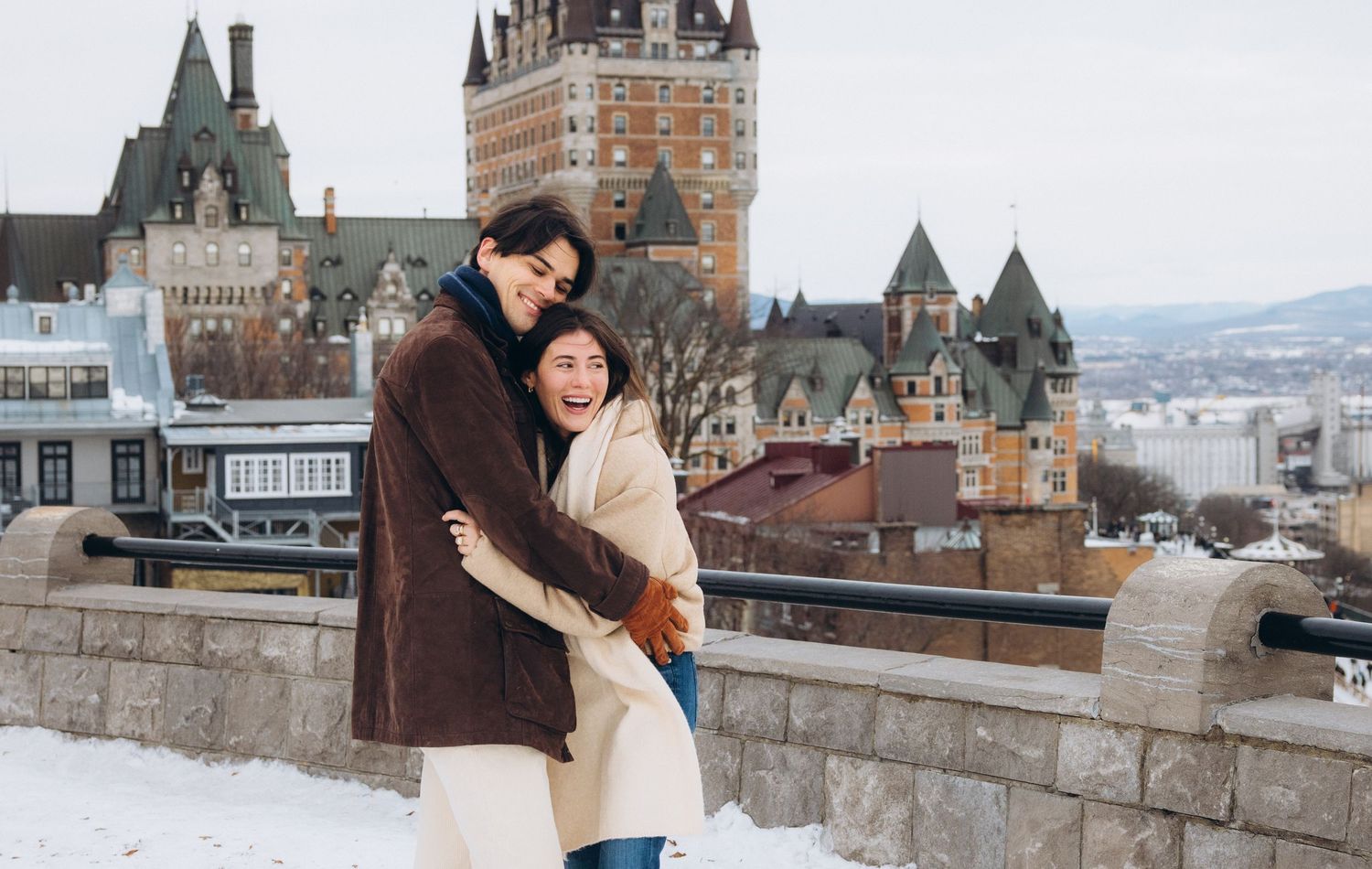Couple embracing in winter at Quebec City with Chateau Frontenac castle in snowy background.