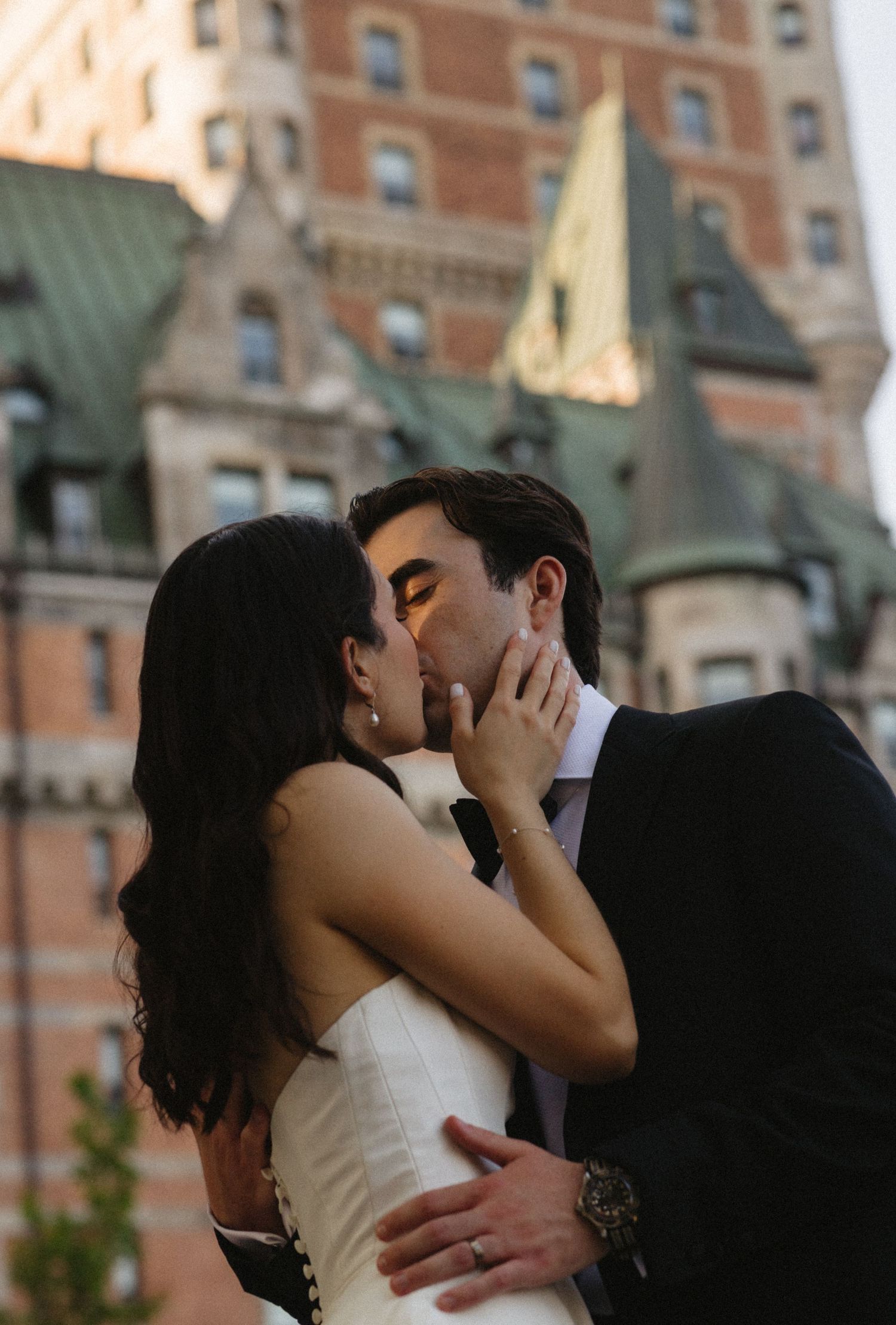 A romantic couple share an intimate kiss in front of the iconic Chateau Frontenac in Quebec City.