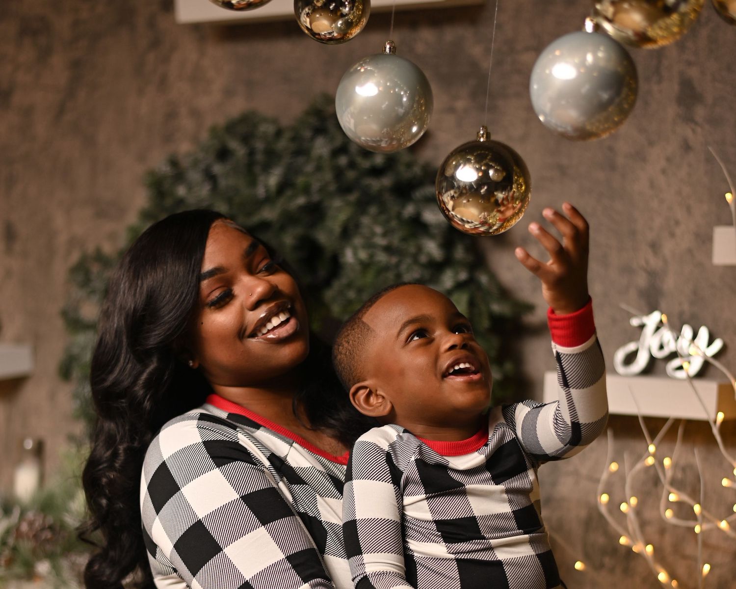 A couple in matching buffalo plaid outfits laughs together while celebrating during a festive holiday photoshoot.