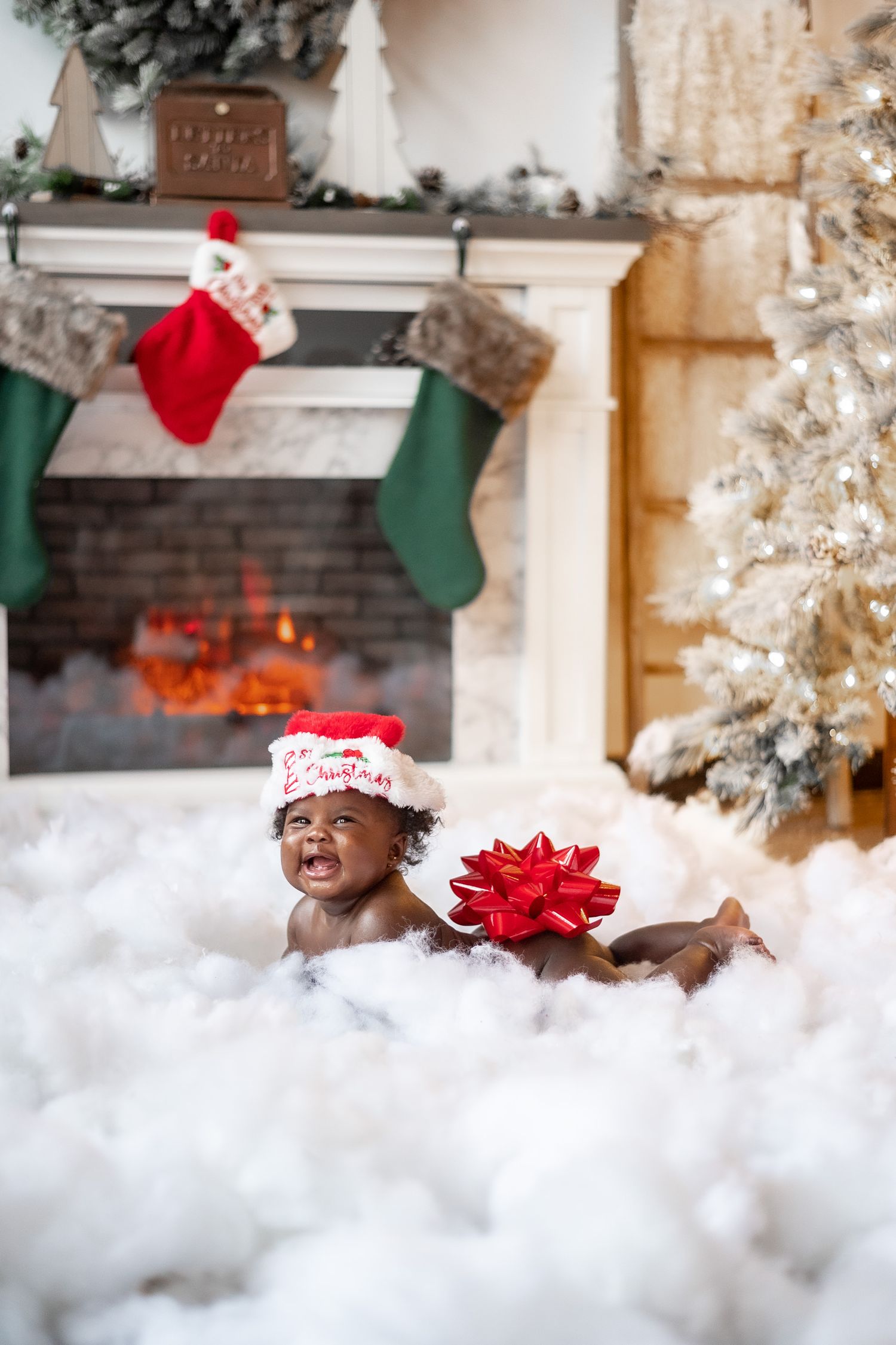 A festive Christmas scene with stockings hung on a mantle, white fluffy decorative snow, and red holiday accents.