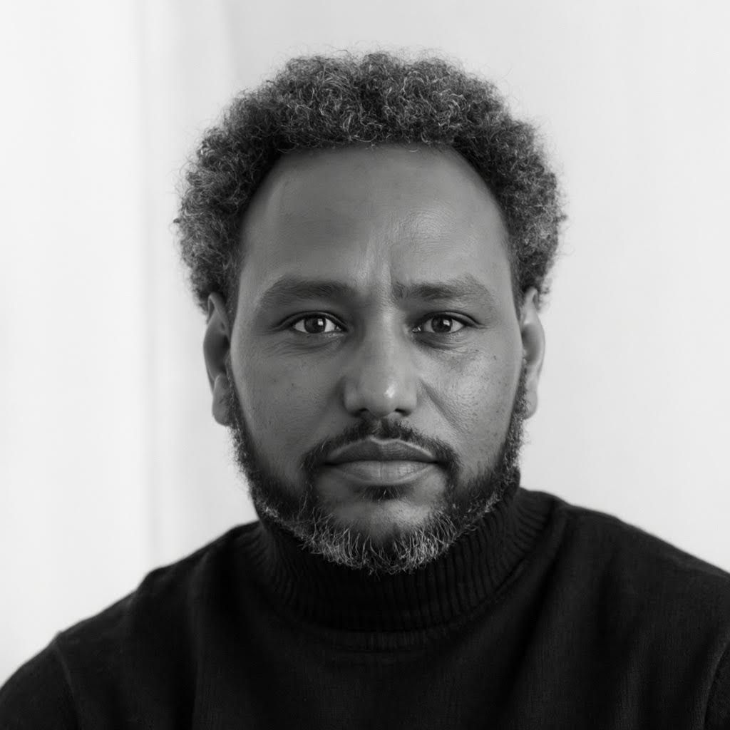 Man with curly hair and facial hair photographed in a series of black and white progressive headshots.