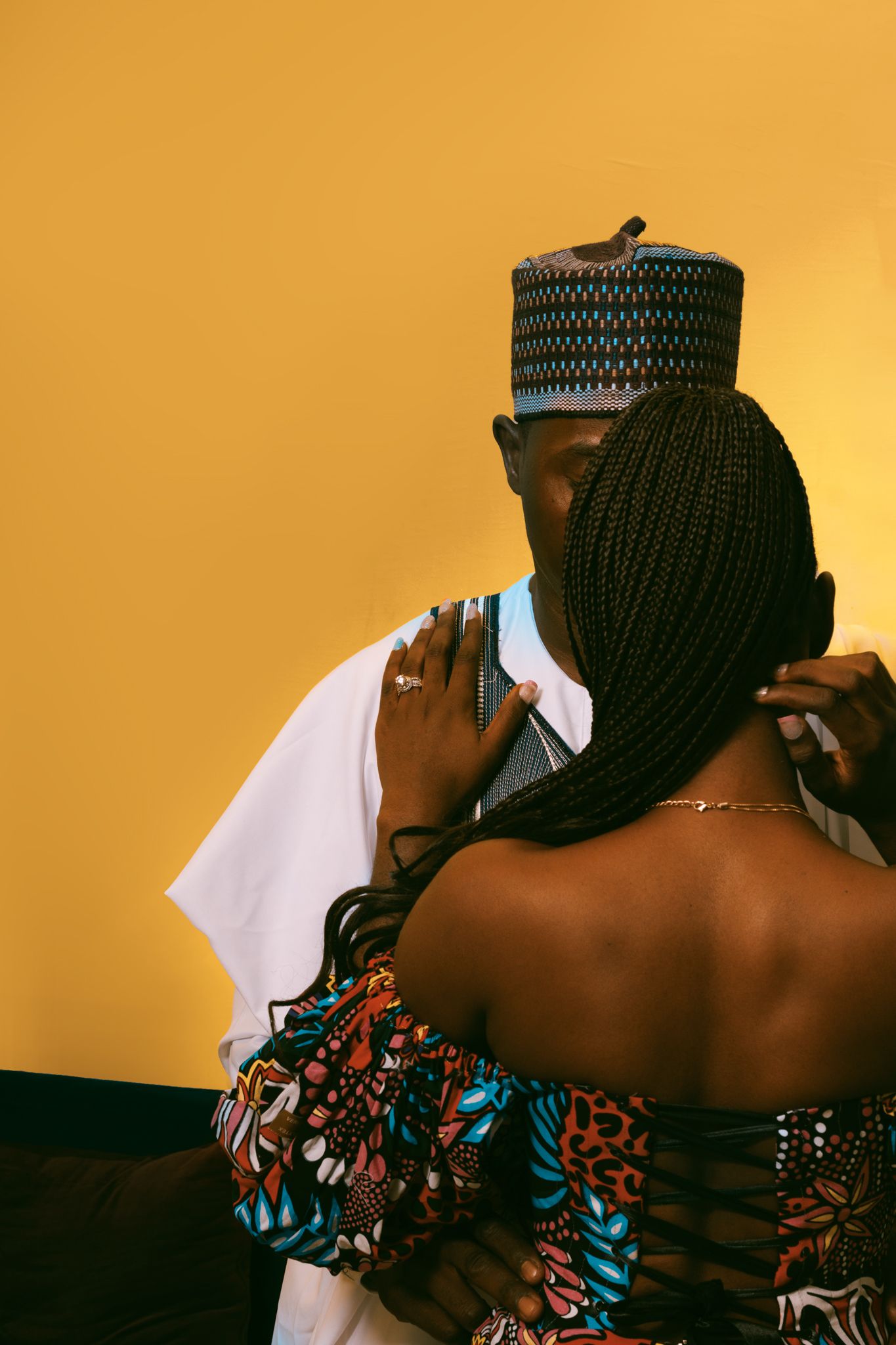 Romantic portrait of a couple embracing against an orange background.