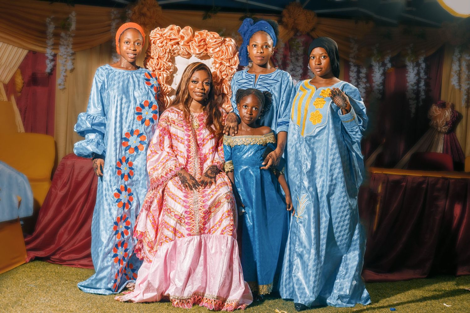 Group photo of people wearing traditional African boubous in blue and pink colors at a celebration.