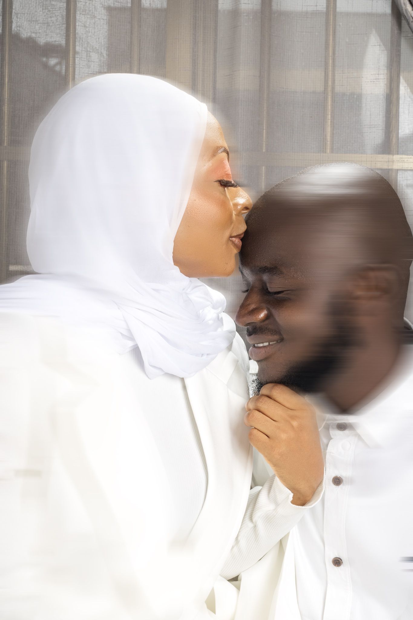 Intimate portrait of a couple in white clothing sharing a tender moment.