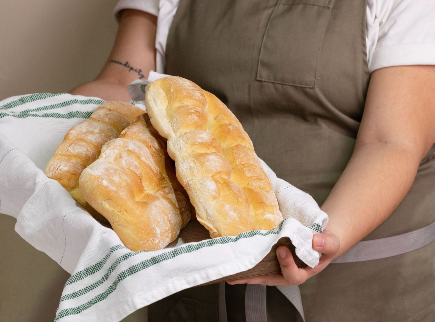 Fresh baked bread rolls wrapped in white kitchen towels.