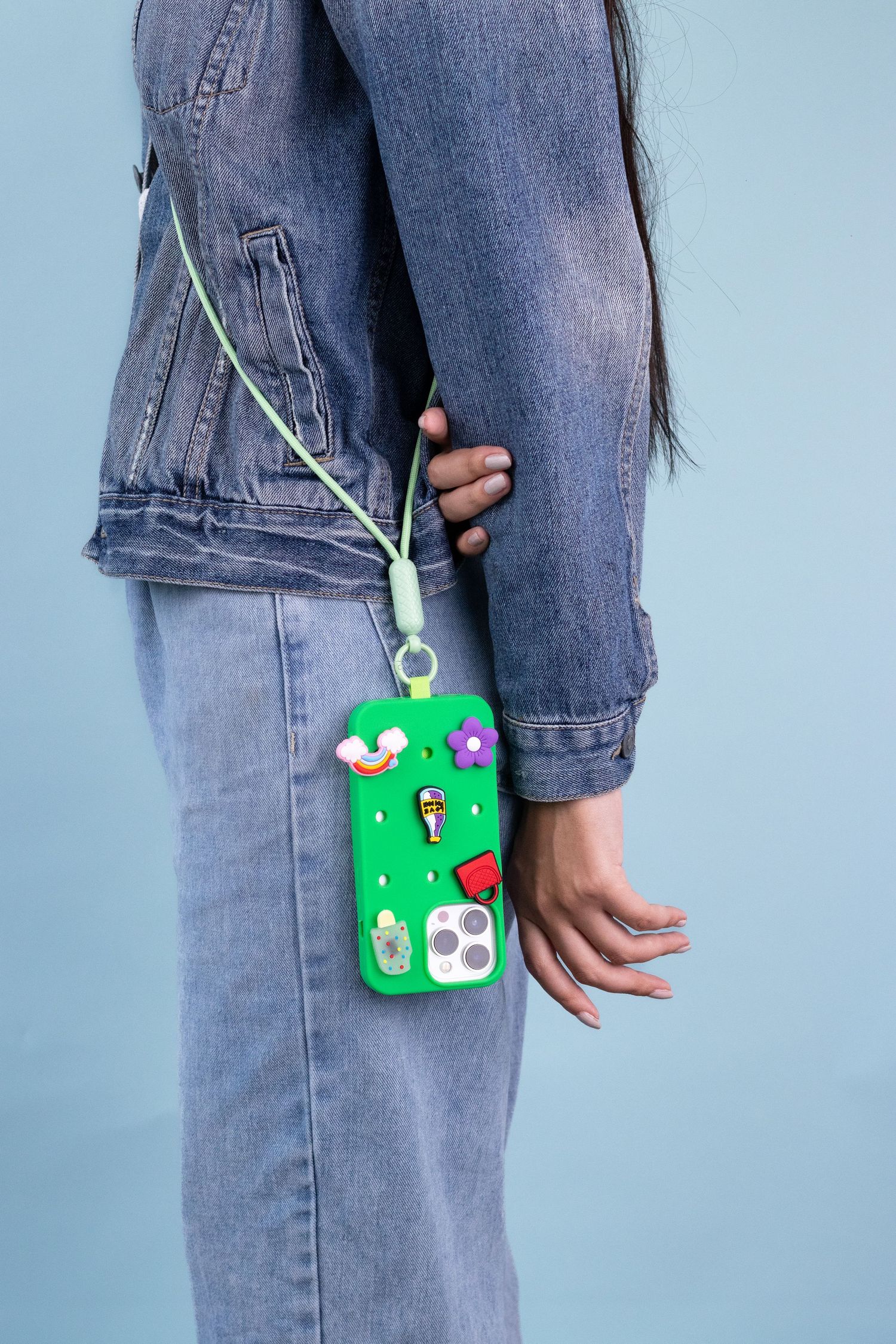Person wearing denim jeans with a green keychain accessory attached.